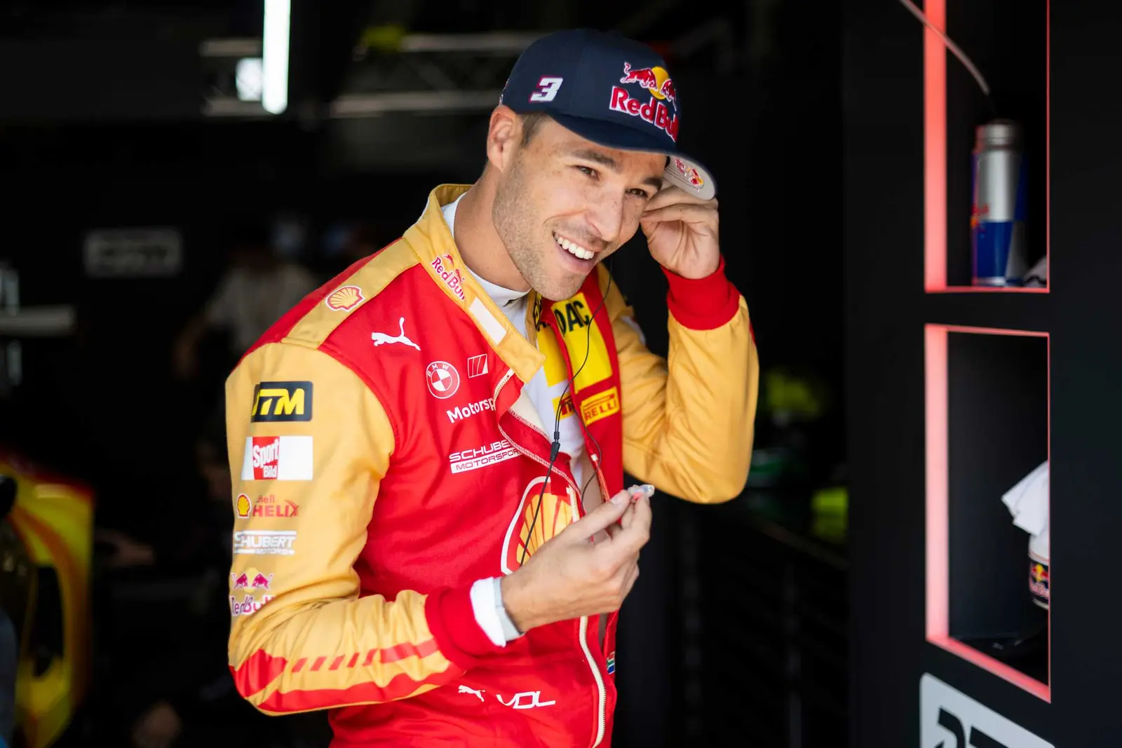 BMW M works driver Kelvin van der Linde smiling in his race suit in the garage